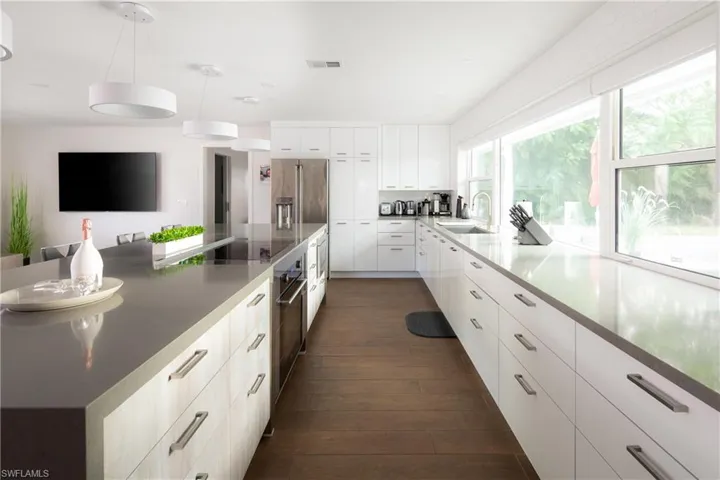 Kitchen featuring decorative light fixtures, sink, dark hardwood / wood-style floors, and white cabinets