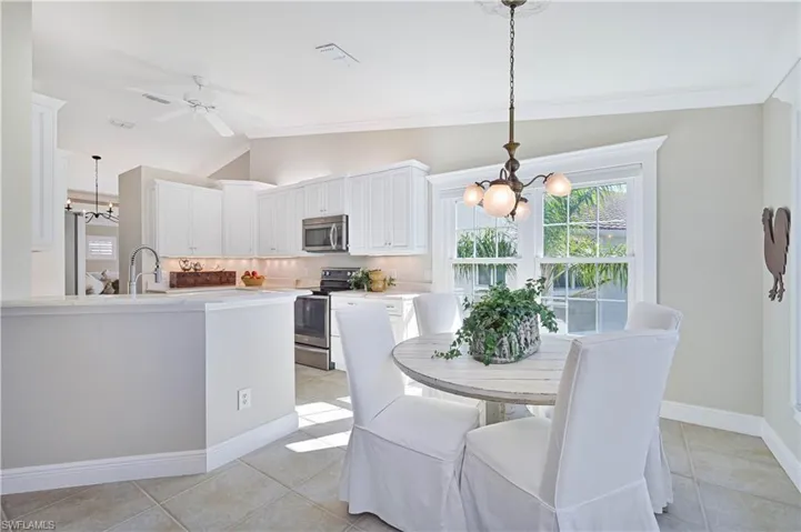 Dining space featuring a chandelier, light tile patterned flooring, lofted ceiling, ornamental molding, and ceiling fan