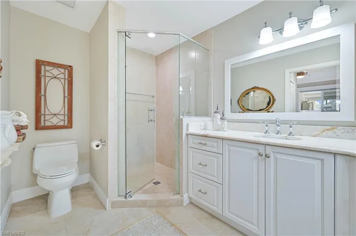Full bath with a shower stall, vanity, light tile patterned floors, and a ceiling fan