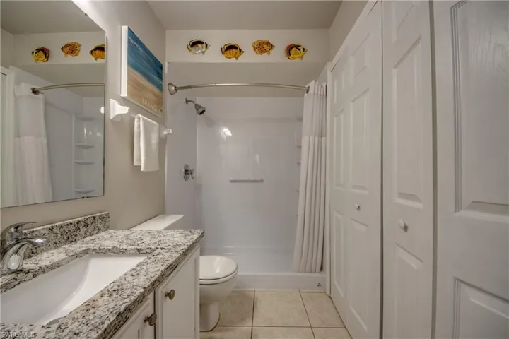 Secondary bath with granite counters, vanity storage, walk-in shower