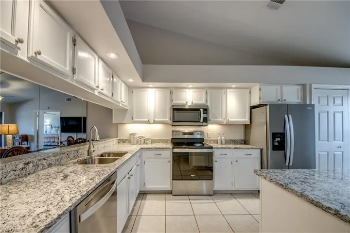 Light, open kitchen with tile flooring & vaulted ceiling