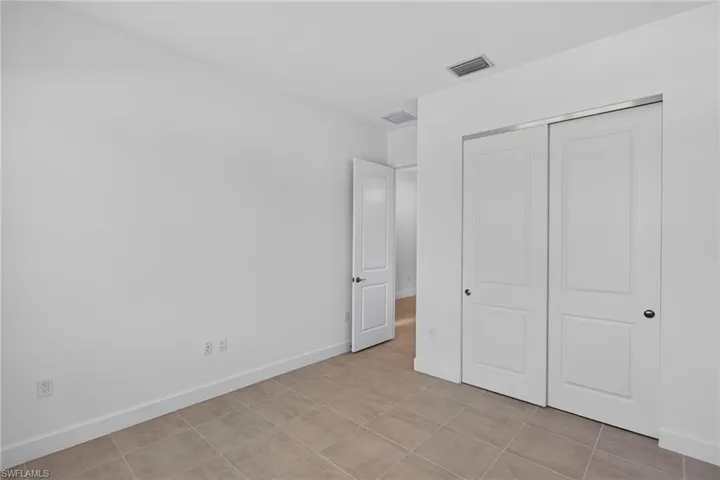 Room featuring neutral-toned tile flooring, white baseboards, and bright white walls