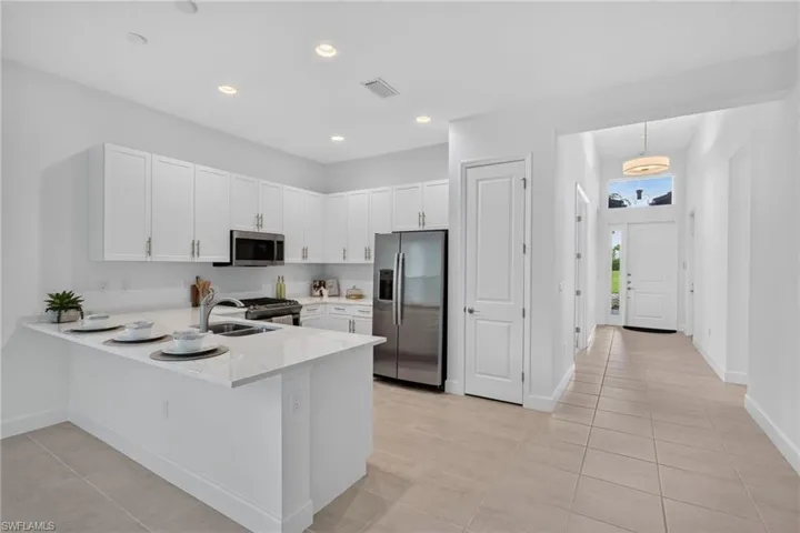 Modern kitchen featuring white shaker cabinetry, stainless steel appliances, a white stone island with an undermount sink, and recessed lighting