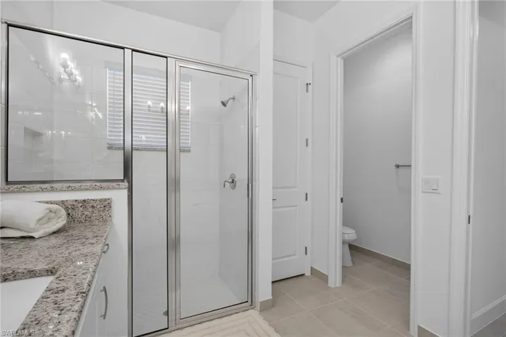 Glass-enclosed shower with chrome fixtures and white tiled walls