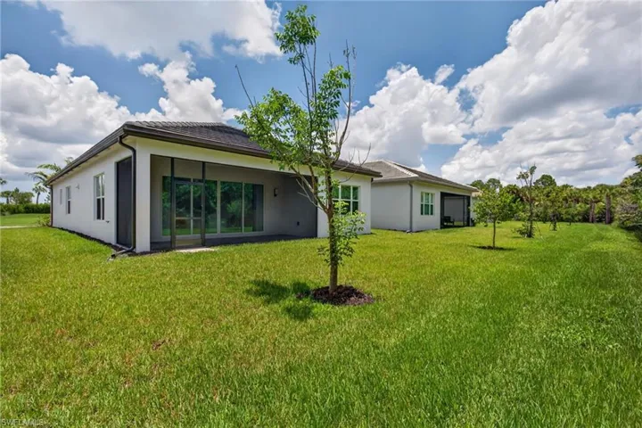 Expansive grassy yard surrounding a contemporary stucco exterior with a screened patio