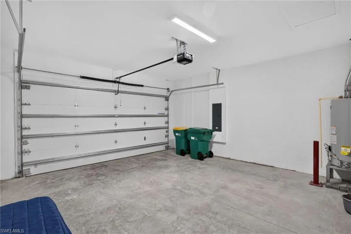 Spacious garage with a sectional overhead door, automatic opener, concrete flooring, and a water heater