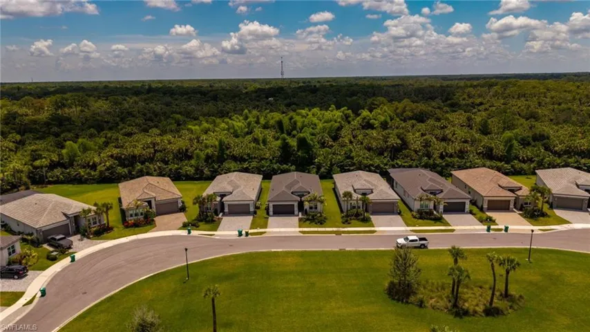 Residential street featuring single-story homes with attached garages, paved driveways, and manicured lawns