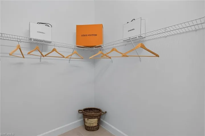 Corner closet featuring white wire shelving and hanging rods