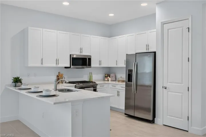 Modern kitchen featuring white cabinetry, light-toned countertops, stainless steel appliances, and recessed lighting