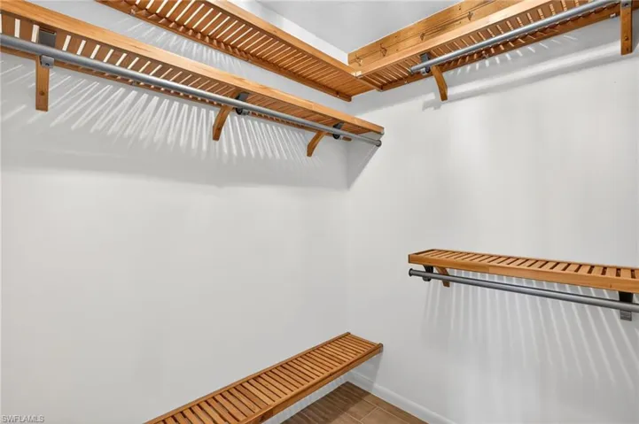 Custom closet system featuring slatted wood shelving and metal hanging rods
