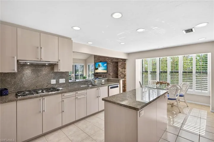 Kitchen featuring a central island with a stone countertop, extensive cabinetry, and a gas cooktop