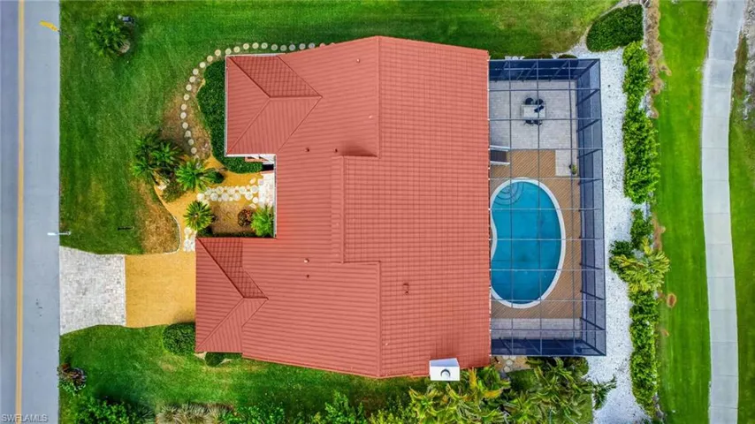 Red tile roof architecture with a screened-in swimming pool and a paved patio area