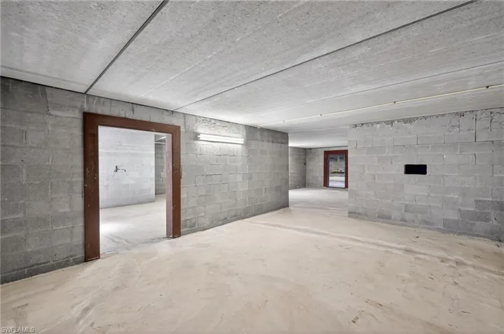 Spacious unfinished room featuring concrete block walls and a concrete floor