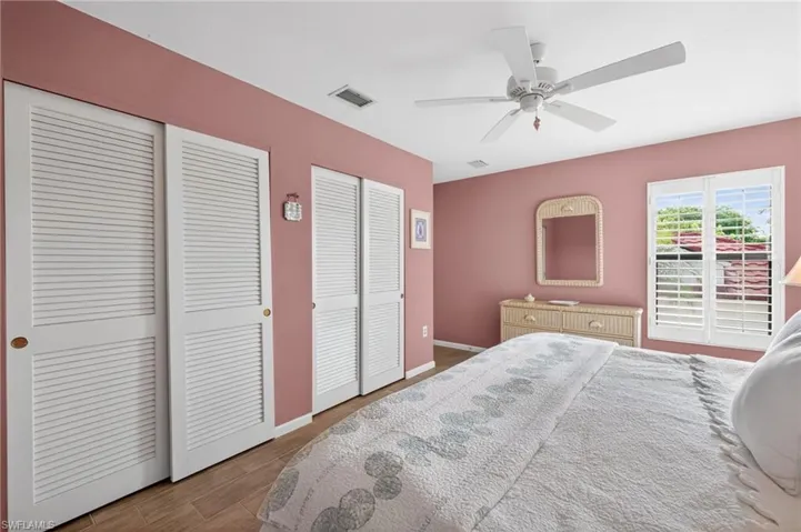 Louvered bi-fold closet doors, wood-finish flooring, and a ceiling fan with light fixture