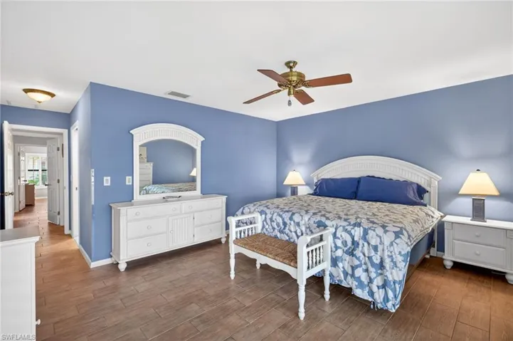 Spacious bedroom featuring wood-finish flooring, a ceiling fan, and crisp white trim