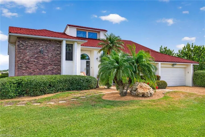 Red tile roof residence featuring a white stucco exterior with a prominent brick facade accent