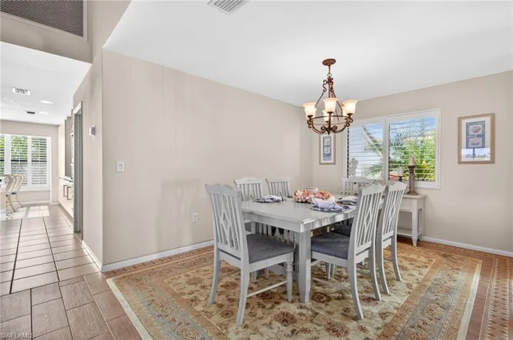 Dining space featuring a decorative chandelier, white plantation shutters, and wood-finish flooring