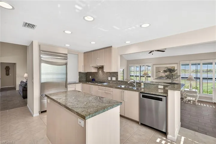 Kitchen featuring a center island with granite countertop, stainless steel appliances, recessed lighting, and light wood-finish cabinetry