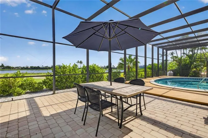 Screened lanai featuring a paver patio and an in-ground spa with wood-finish decking