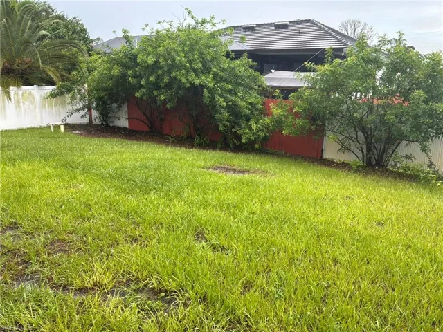 Expansive backyard featuring a green lawn, perimeter fencing, and mature landscaping providing natural screening