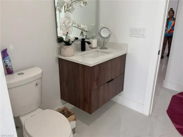 Floating wood-finish vanity with an integrated rectangular sink, light-toned countertop, and matte black faucet