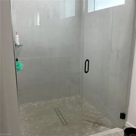 Glass-enclosed shower featuring large format wall tiling, a rectangular linear drain, and a mosaic tile shower floor