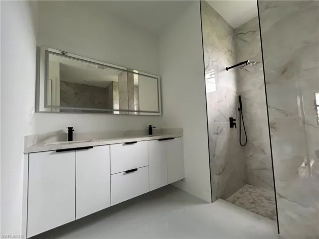 Bathroom featuring double vanity and a marble finish shower