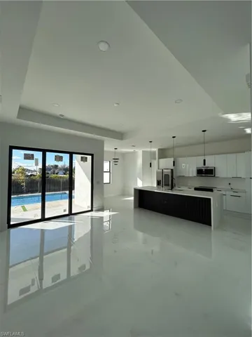Kitchen featuring a large island, modern cabinets, pendant lighting, a raised ceiling, and freestanding refrigerator
