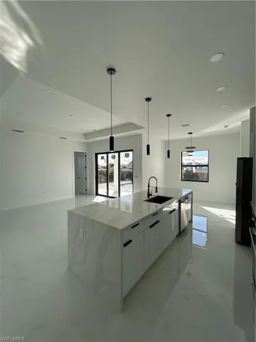 Kitchen with white cabinetry, modern cabinets, light stone counters, pendant lighting, and a large island