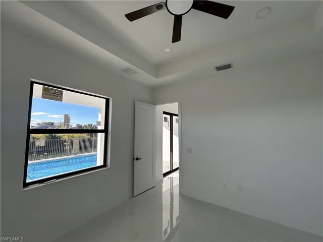Spare room featuring a ceiling fan, a raised ceiling, recessed lighting, and concrete flooring