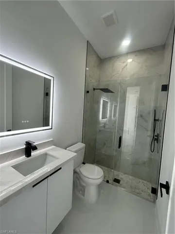 Bathroom with vanity and a marble finish shower