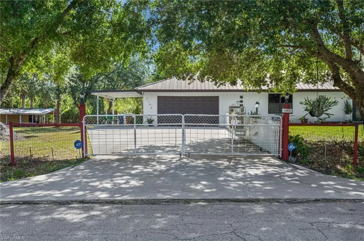 Ranch-style house featuring a fenced front yard, metal roof, and a garage