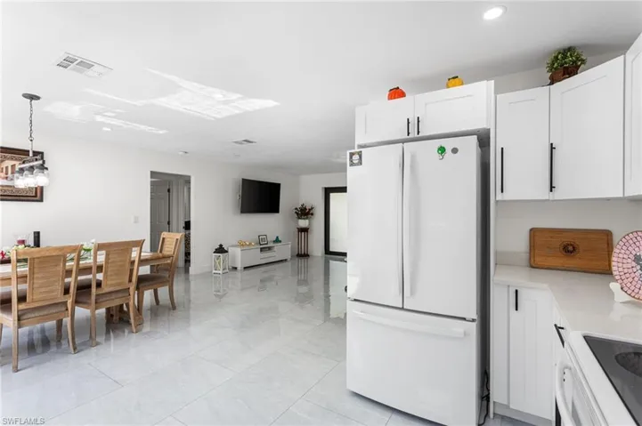 Kitchen featuring stove, white cabinets, light countertops, visible vents, and freestanding refrigerator