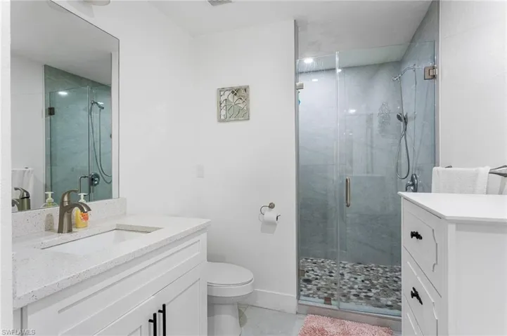 Full bathroom featuring toilet, vanity, and a stall shower
