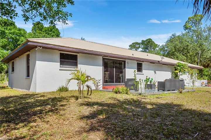 Back of house featuring a patio area, a lawn, and stucco siding