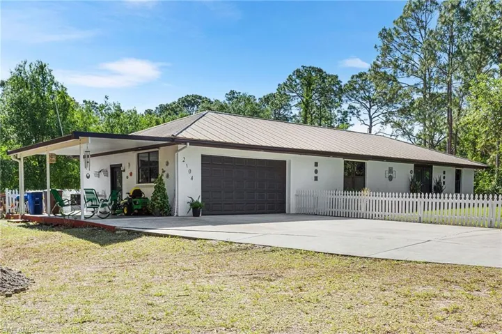 Ranch-style house with concrete driveway, a front lawn, an attached garage, fence, and stucco siding