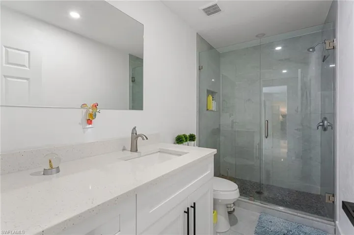 Full bathroom with visible vents, toilet, a stall shower, and vanity
