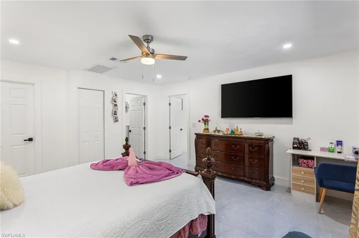 Bedroom with a closet, light tile patterned flooring, ceiling fan, visible vents, and recessed lighting