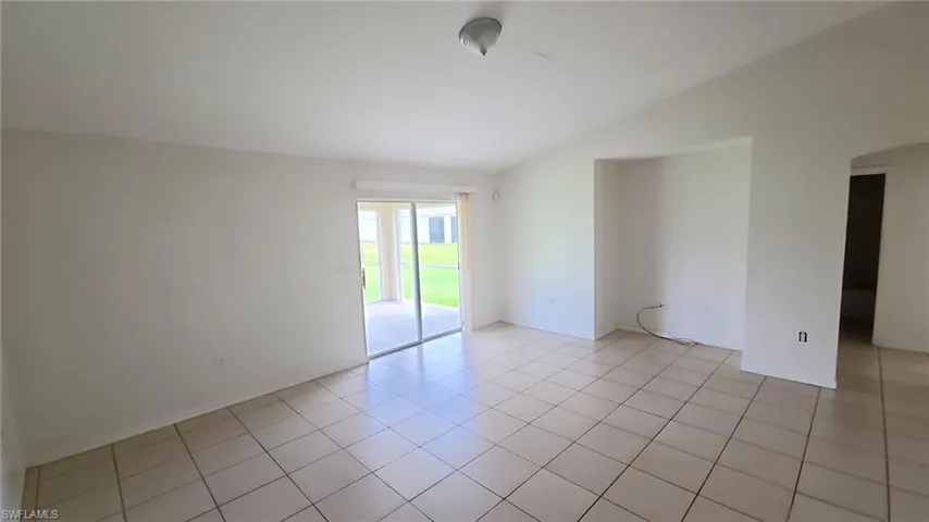 Spacious interior room featuring tile flooring, vaulted ceiling, and built-in wall niche