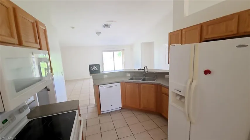 Kitchen featuring wood cabinetry, a double basin sink, and a built-in dishwasher