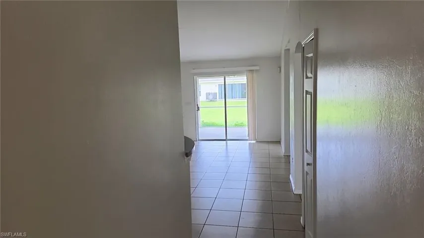 Hallway with neutral tone walls and square tile flooring