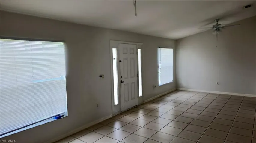 Spacious interior room featuring tile flooring, vaulted ceilings, and a ceiling fan