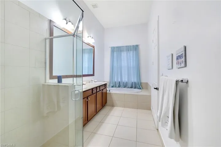 Bathroom with double vanity, light tile patterned floors, a stall shower, and a bath