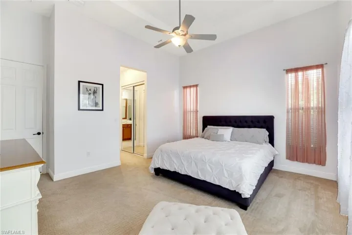 Bedroom with light carpet, a ceiling fan, a closet, and a high ceiling
