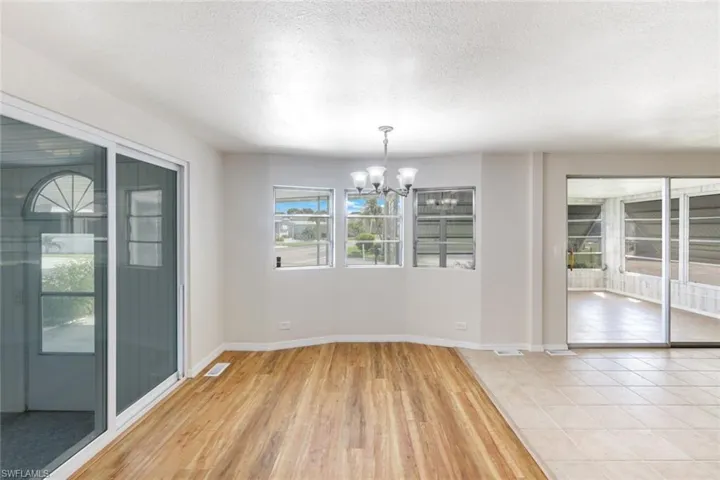 Unfurnished dining area with a chandelier, light wood-type flooring, and a textured ceiling