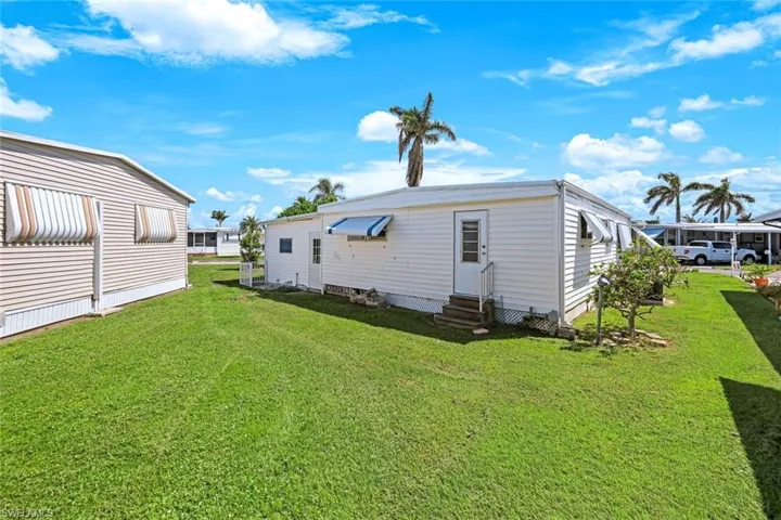 Rear view of house with a lawn and entry steps
