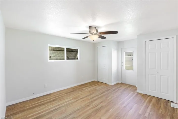 Unfurnished bedroom with a textured ceiling, multiple closets, light wood finished floors, and ceiling fan