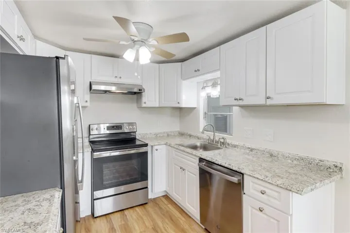 Kitchen featuring appliances with stainless steel finishes, light wood finished floors, under cabinet range hood, white cabinetry, and a ceiling fan