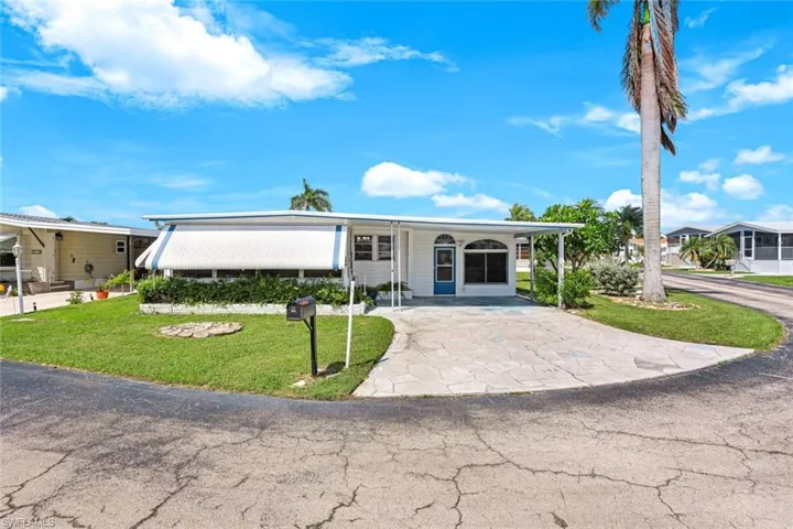 Manufactured / mobile home with driveway, a carport, a front lawn, and a porch