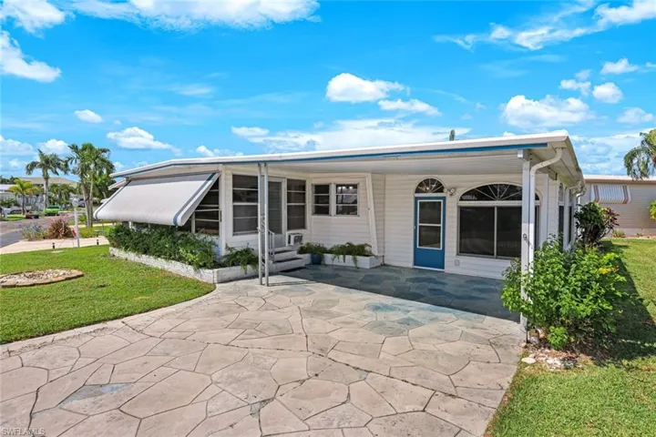 Rear view of property featuring a yard, a patio area, a sunroom, and an attached carport